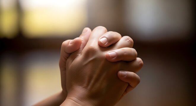 Clenched hands in prayer for spiritual guidance and hope indoors