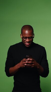 A happy man using his phone with a green screen background. Perfect for showcasing apps, websites, and businesses targeting men or millennials.