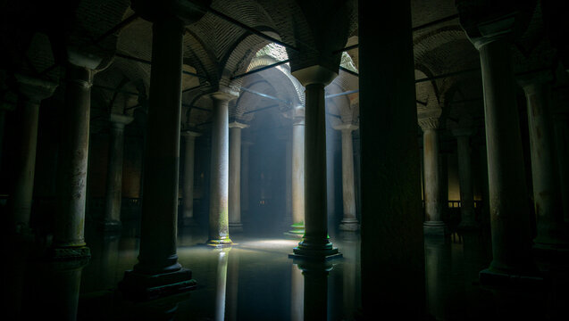 Dark and moody underground cistern interior with stone pillars, vaulted ceilings, and calm water reflecting the dim light in a quiet space