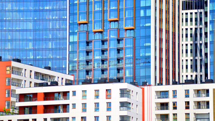 A low-rise residential building stands against a backdrop of tall glass buildings. An urban quarter of modern architecture. © Grand Warszawski
