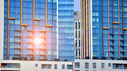 A low-rise residential building stands against a backdrop of tall glass buildings. An urban quarter of modern architecture. © Grand Warszawski