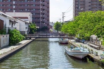 加茂川を繋ぐ木造の小橋と水面に浮かぶ小舟、白壁土蔵が織りなす下町の風情/Downtown Atmosphere Created by Small Wooden Bridges Spanning the Kamogawa River, Small Boats Floating on the Water, and White-Walled Storehouses © Taketo Miyajima