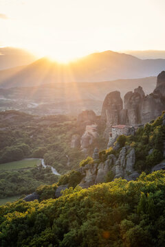 Amazing panoramic view of the Meteora valley with the monasteries in the golden hour of the sunset against the background of the setting sun, near Kastraki, Greece.