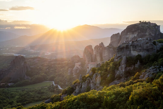 Amazing panoramic view of the Meteora valley with the monasteries in the golden hour of the sunset against the background of the setting sun, near Kastraki, Greece.