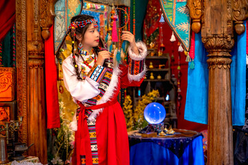 Obraz premium Pretty East Asian girl wearing authentic traditional Mongolian national clothing, posing inside lively and brightly colored room that reflects a rich cultural heritage