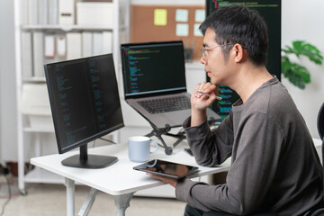 Obraz premium Male software developer working on code at modern desktop with multiple monitors