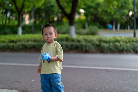 Little child holding bubble maker near park path