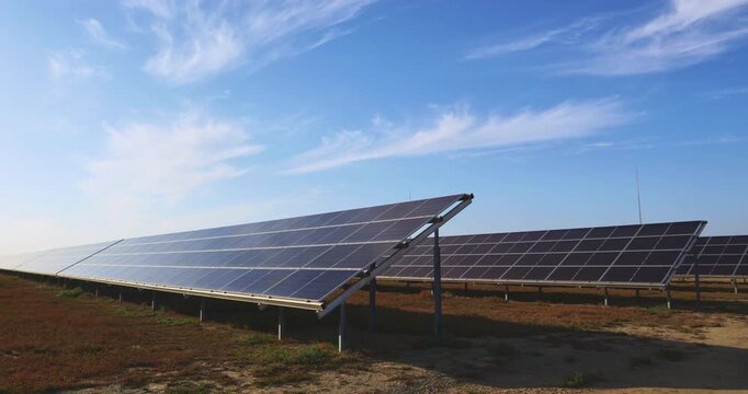 Solar power plant view captures long photovoltaic arrays across open field with light clouds for renewable electricity sustainability and energy transition use