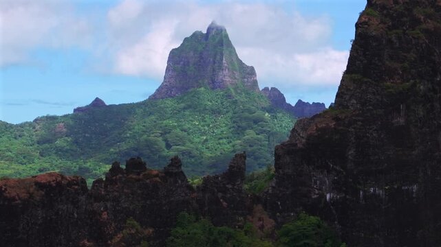 Moorea's dramatic volcanic tall jagged peaks rugged terrain Mount Rotui Mt Toheia French Polynesia aerial drone Belvedere Lookout Cooks Opunohu Bay sunny morning blue sky clouds low fog circle left