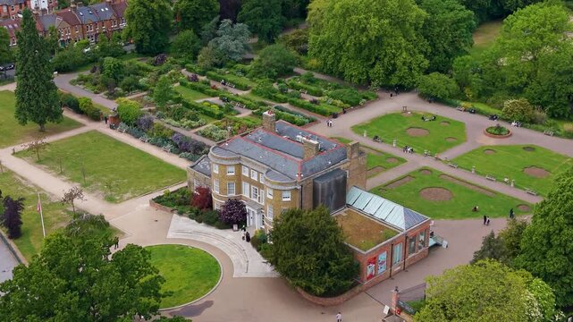 William Morris House at Lloyd Park, Walthamstow, London as a drone descends over gardens, paths and museum building, revealing the surrounding green parkland and visitors below.