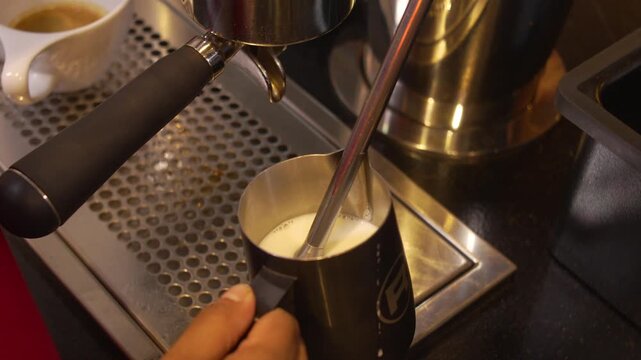 Barista Steaming Fresh Milk in Metal Pitcher with Steam Wand at Professional Espresso Machine, Specialty Coffee Preparation Close-Up