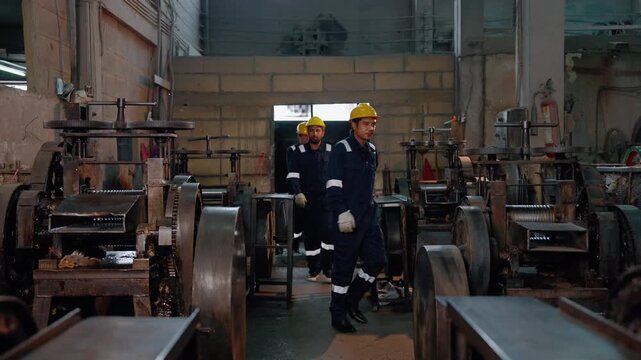 Industrial workers and technicians operating heavy machinery in a manufacturing facility. Production process, industrial workforce and factory operations concept.
