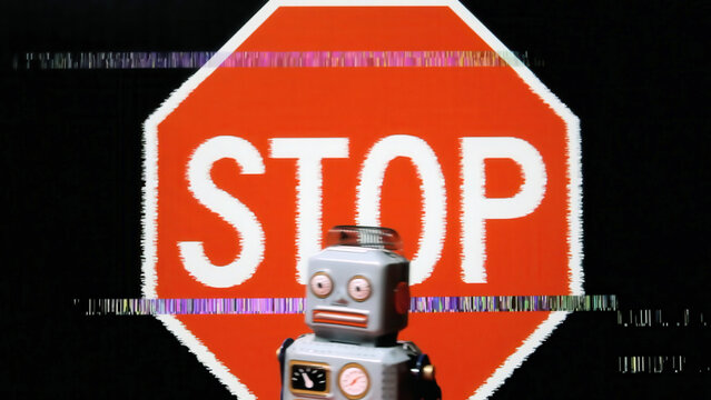 Retro robot toy stands before glitching red stop sign with digital distortion effects on black . Pixelated corruption and colorful scan lines create cyberpunk aesthetic. AI warning .
