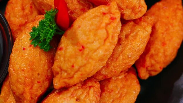 Crab flavoured nugget with soy sauce on black plate.