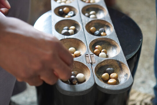 Close up shot of a hand playing Ayo African board game 