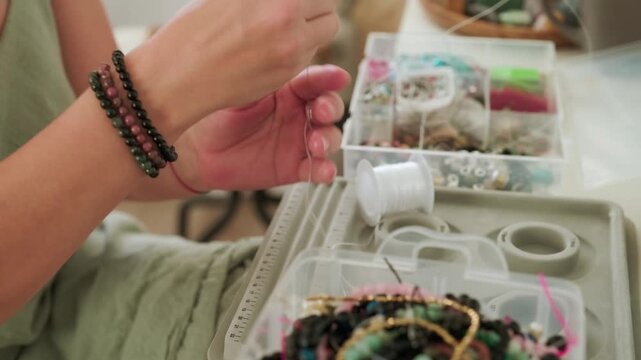 Close-up of hands of a woman artisan creating natural stone bracelets