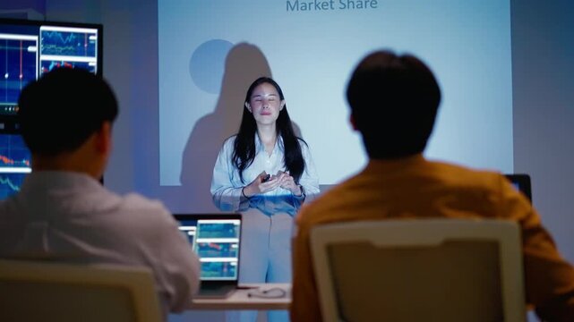 Asian businesswoman or speaker presenting a strategic marketing vision on a global shipping route map.Showing logistics infographics,statistics and product distribution on screen during a conference.