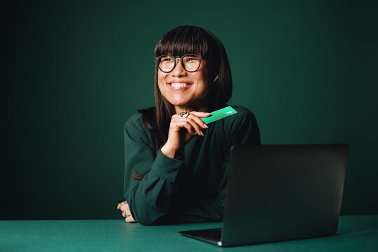 Woman using laptop and credit card for online payment in monochromatic studio setting
