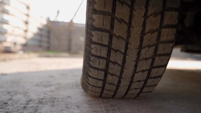 Low angle close-up of car tire tread on dusty ground at construction site