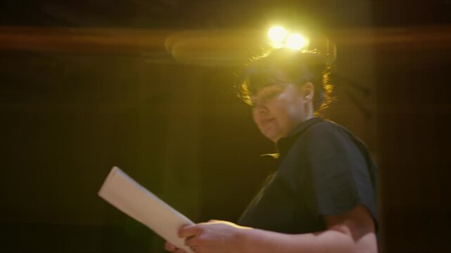 Focused theater performers rehearsing lines on stage under warm spotlight, holding scripts and practicing dialogue during an intimate dramatic rehearsal session