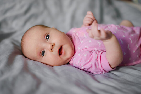 Happy Newborn Baby Lying On Soft Bed