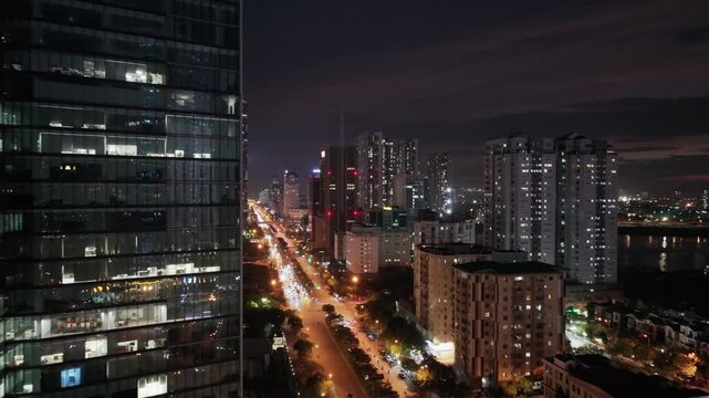 Illuminated boulevard near Cau Giay Lake at night with modern towers and dense urban development in Hanoi.