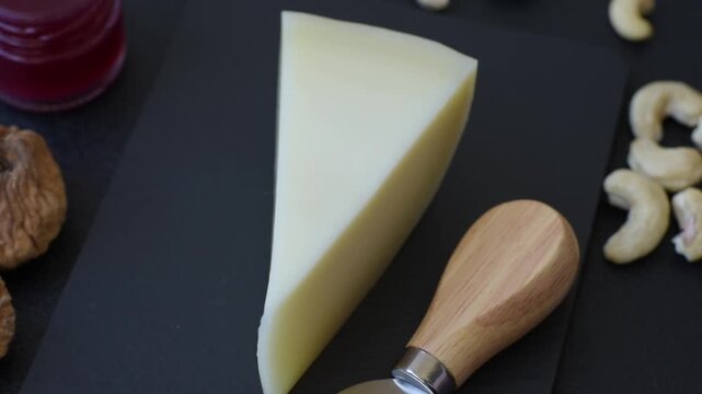 Aged cheese in a triangular block with jam, figs, and nuts. Aged cheese as a food background for your design