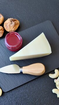 Aged cheese in a triangular block with jam, figs, and nuts. Aged cheese as a food background for your design