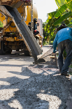 Construction worker leveling fresh wet cement pouring from a mixer truck
