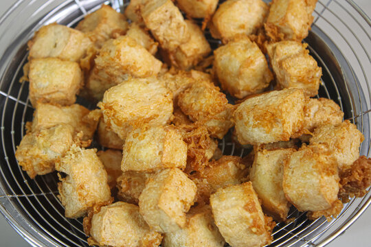 Crispy fried tofu cubes on a metal oil strainer basket