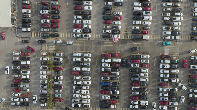 Bird's-eye view of a busy parking facility with hundreds of parked vehicles arranged in structured rows.