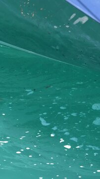 Close Up of Bilge Pump Water Discharging from Blue Boat Hull