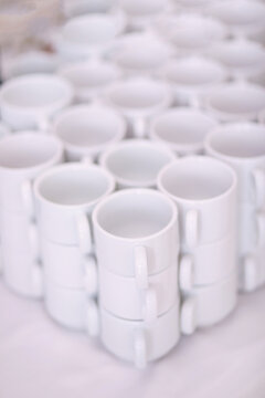 Stacked white ceramic coffee cups arranged in neat rows for serving at an event or cafe