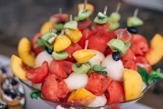 Colorful fruit skewers and melon balls in a glass bowl for summer party dessert display