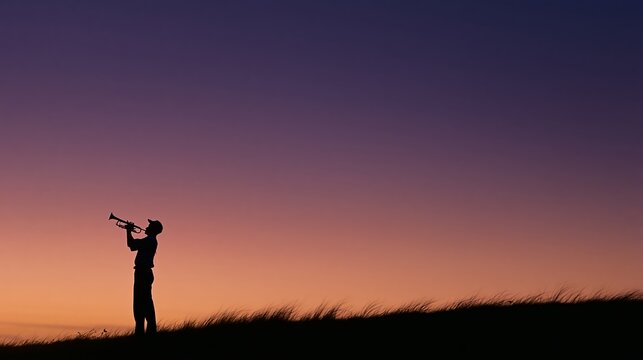 Silhouette of a bugler standing on a hilltop playing at sunset