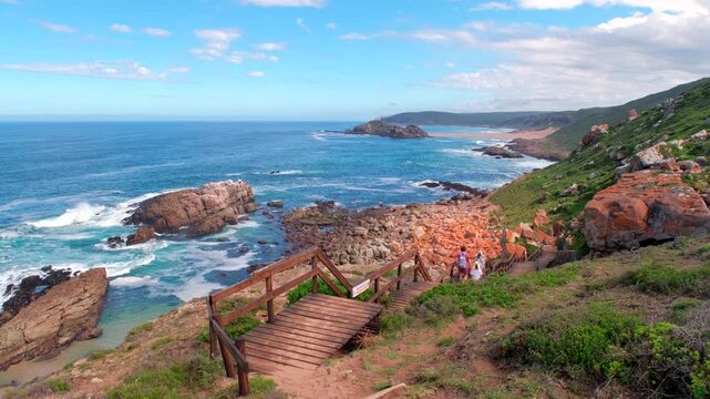 Family hike down wooden boardwalk at Robberg nature reserve with scenic views