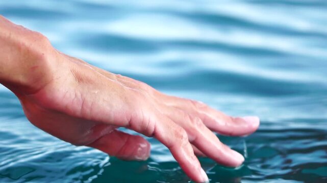 Hand water touch, person's hand gently touching the surface of calm blue ocean water, feeling serene and refreshing