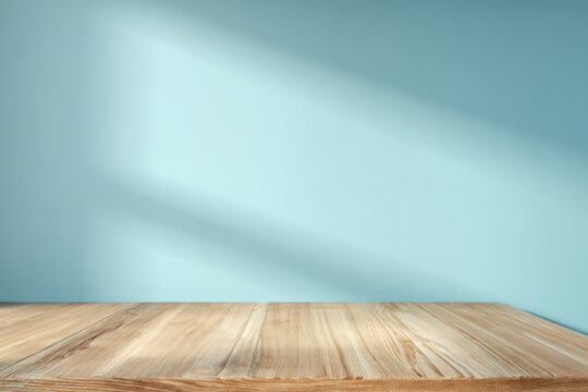 A warm wooden table against a serene blue wall, bathed in soft light and shadows, creating a tranquil atmosphere.
