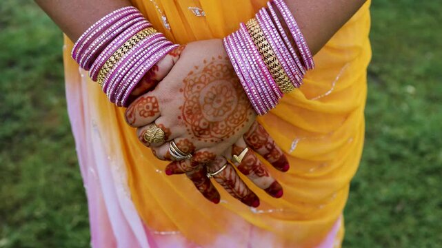 indian bridal mehndi art on hands with colorful bangles rings and traditional saree outfit