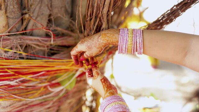women hand offering spiritual prayer threads knot around ancient banyan tree during indian festival