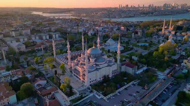 Sultan Ahmed Mosque with its minarets and domes bathed in golden light against the Istanbul cityscape and Bosphorus. Fabulous aerial view fly push forward panorama drone