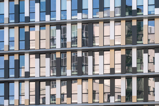 Patterned facade repeats across office windows, with blue reflections and beige panels building urban architecture into a tight grid