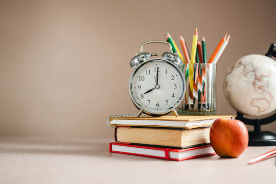 Student learning materials with globe and alarm clock, classroom preparation concept, copy space