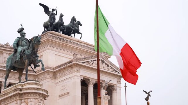Waving italian flag in front of national monument to victor emmanuel ii in rome.