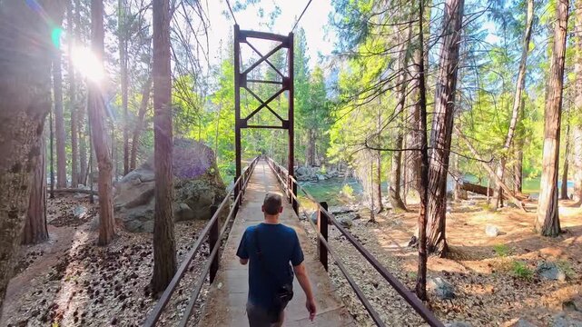 Man Hikes Across Suspension Bridge Over Kings River in Cedar Grove area of Kings Canyon National Park