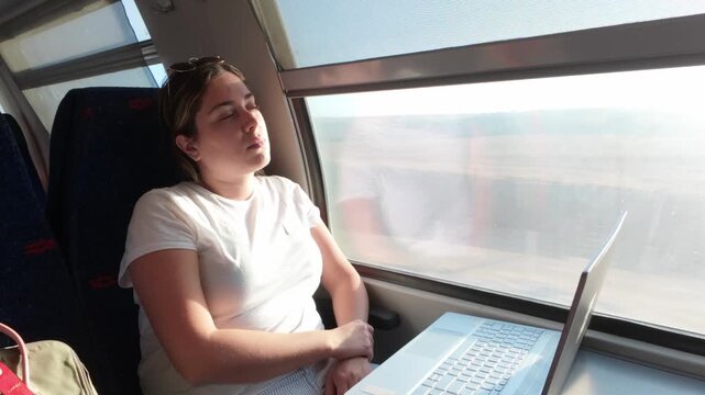 Exhausted Woman Sleeping on a Train During a Sunny Commute
