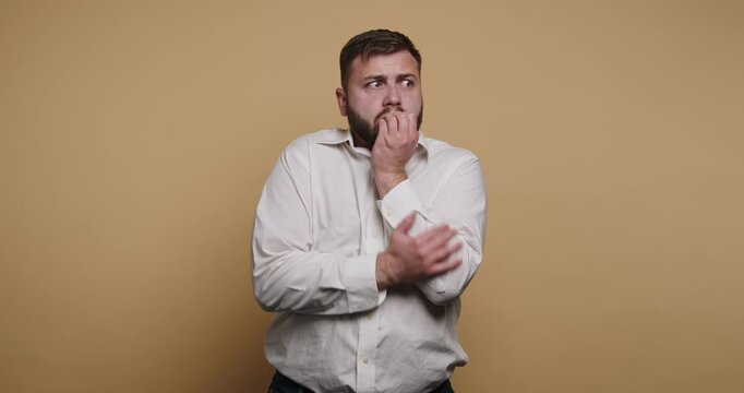 Man shows nervous behavior in a studio with a plain background during daytime