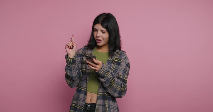 Woman using smartphone to share tips in a studio with pink background