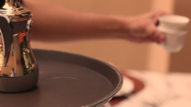 Waiter serving traditional tea cups to guest in elegant restaurant setting
