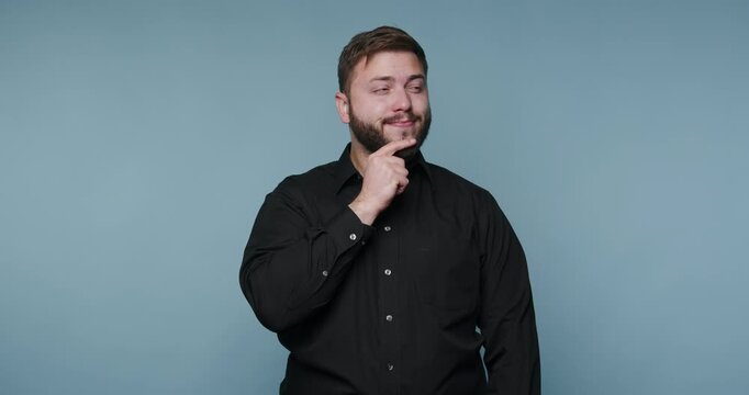 Man thinking and pondering ideas in a studio with blue background in a casual black shirt during the day